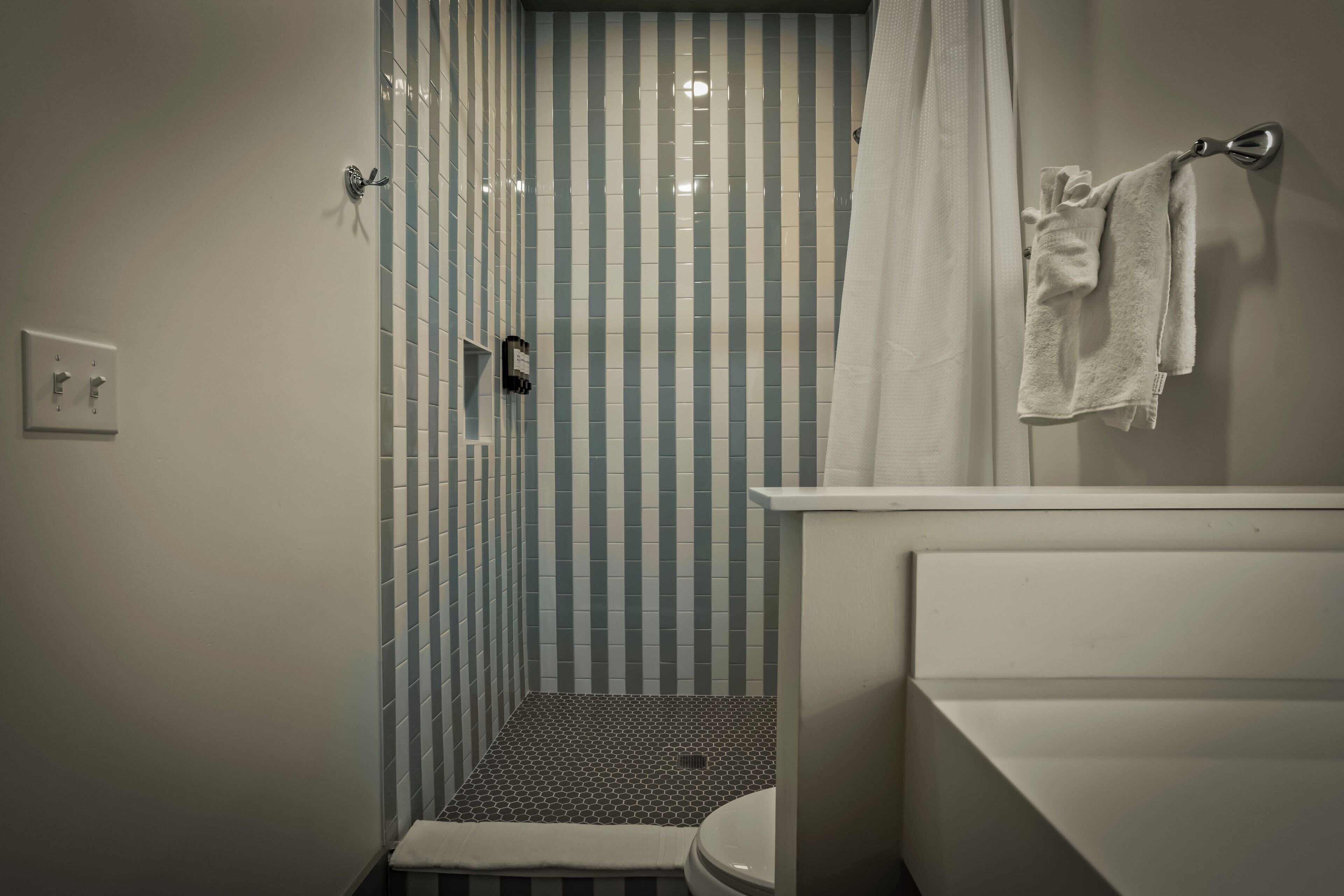Un baño con ducha, inodoro y toallero.