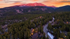 Un paisaje montañoso con un río, un bosque denso y un pequeño poblado con casas.