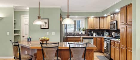 A kitchen with a central island, wooden cabinets, and pendant lighting.