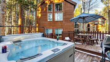Une cabane en bois avec un jacuzzi, un espace salon extérieur et un bâtiment en pierre en arrière-plan.