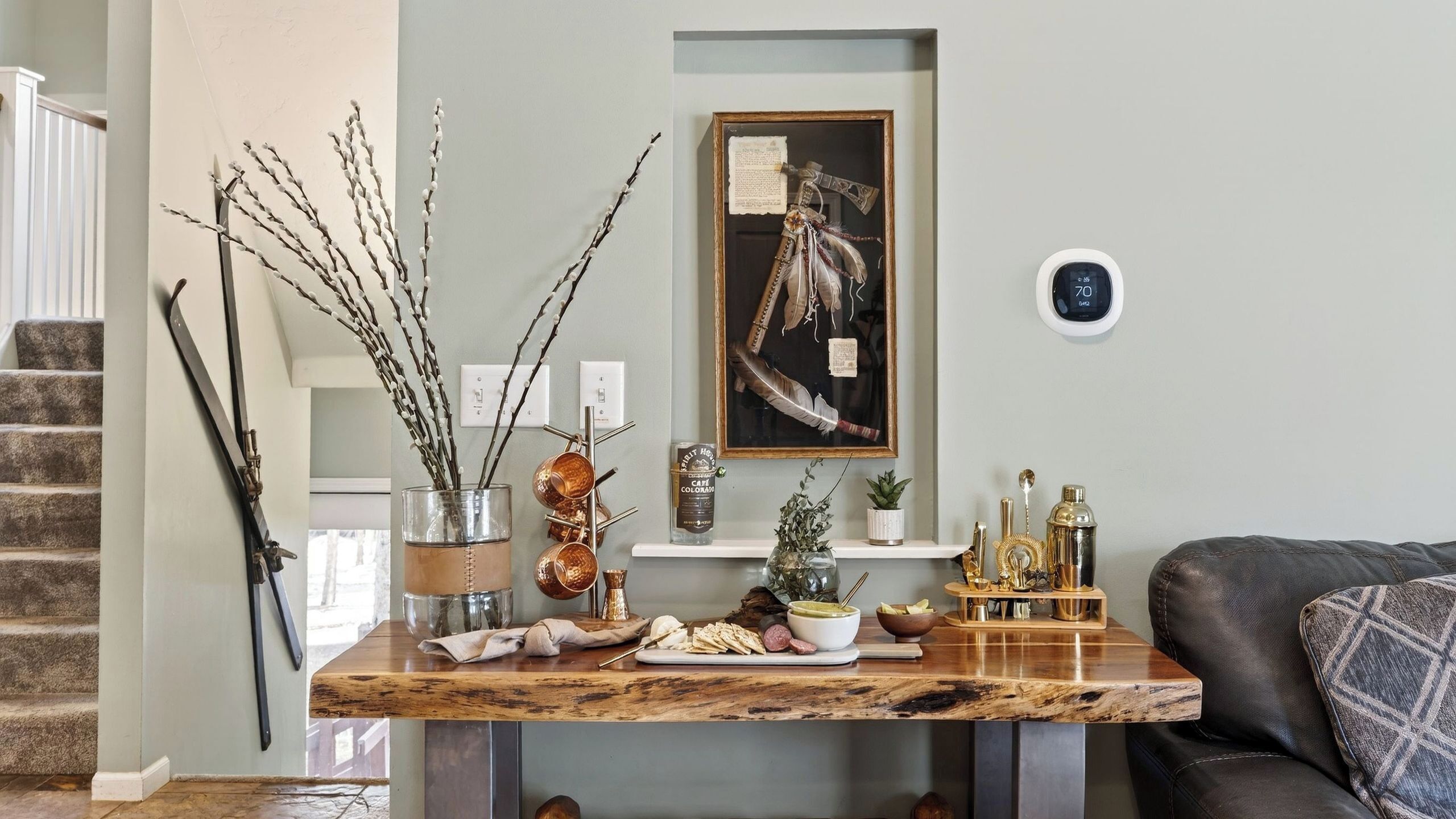 A dining area with a wooden table, a framed artwork, and a clock on the wall.