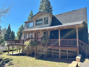 A two-story house with a porch, a covered deck, and a garage. - Hamilton Branch Multi-level Home with Stunning Lake Almanor View (Westwood)
