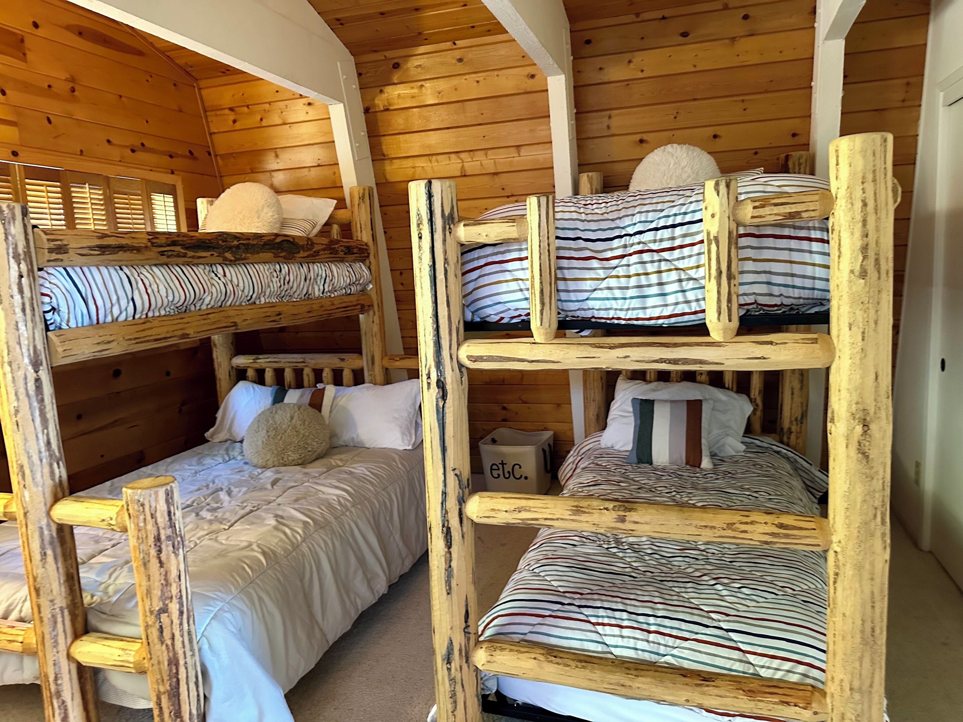 A bunk bed room with wooden walls and a white ceiling.