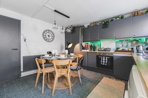 A modern kitchen with a dining table, chairs, and a clock on the wall.