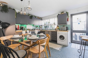 A modern kitchen with a dining area, a washing machine, and a view of the city.