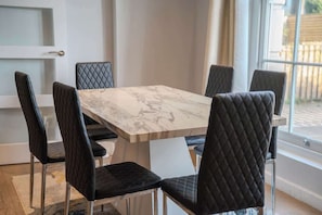 A dining area with a marble table and black upholstered chairs.