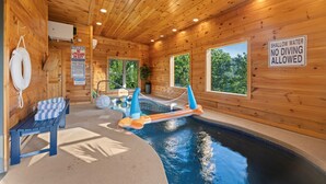 Una cabaña de madera con piscina, una silla de socorrista y un trampolín.