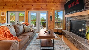 Una sala de estar acogedora con chimenea, señal de Netflix y vistas al exterior.