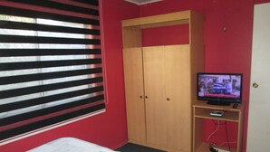 A bedroom with a bed, a wardrobe, a television on a stand, and a window with blinds. - B3 Furnished cabin near downtown Puerto Montt (Puerto Montt)