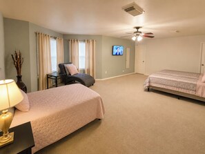 A bedroom with two beds, a chair, a TV, and a ceiling fan. - Sleeps 20 w/Pool Near SeaWorld/6-flags & AFB (San Antonio)