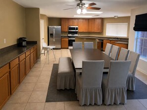A modern kitchen with a dining area, wooden cabinets, a refrigerator, microwave, and a ceiling fan. - Sleeps 20 w/Pool Near SeaWorld/6-flags & AFB (San Antonio)