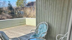 Un espacio al aire libre cubierto con sillas de mimbre y una mesa de vidrio.