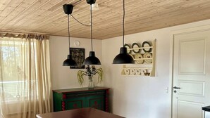 Una cocina con techo de madera, una isla central con taburetes y un esparacimos para platos en la pared.