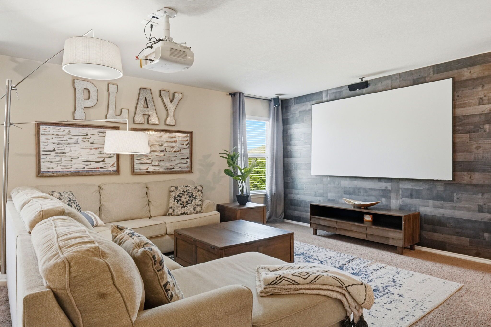 A living room with a sofa, coffee table, lamp, and a large flat-screen TV against a wooden wall.