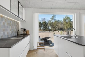 Eine moderne Küche mit einem großen Fenster, einem Einbauofen und einer Kaffeemaschine.