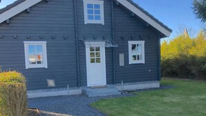 A two-story house with a gabled roof, a front porch, and a small front yard. - Cozy log cabin near beach and forest (Strøby)