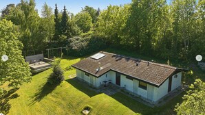 Ett tvåvåningshus med ett platt tak, en liten veranda och en trädgård.