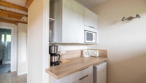Eine kompakte Küche mit Mikrowelle, Kaffeemaschine, Toaster und kleinem Kühlschrank.