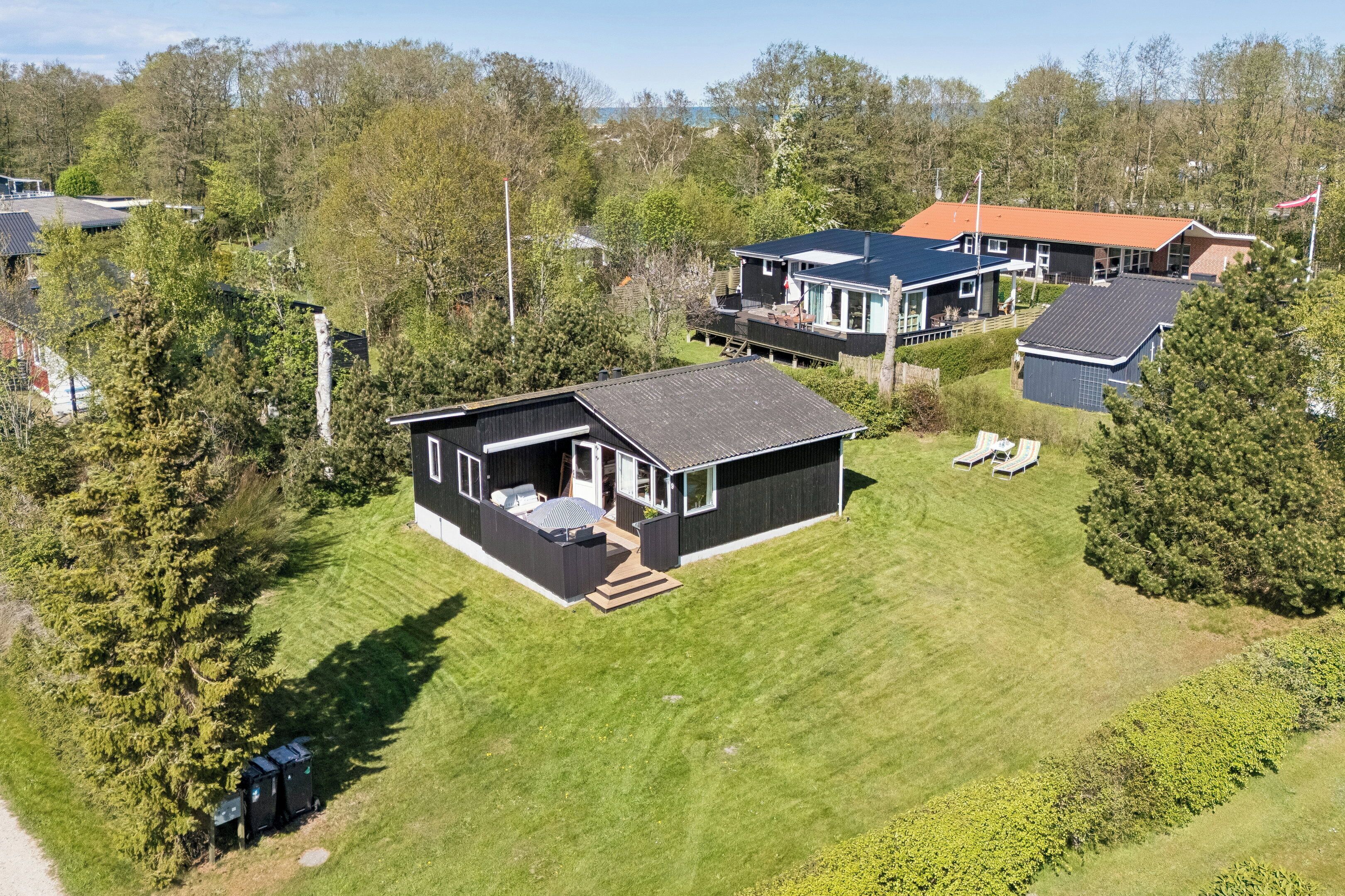 A modern house with a large deck, a separate garage, and a well-maintained lawn.
