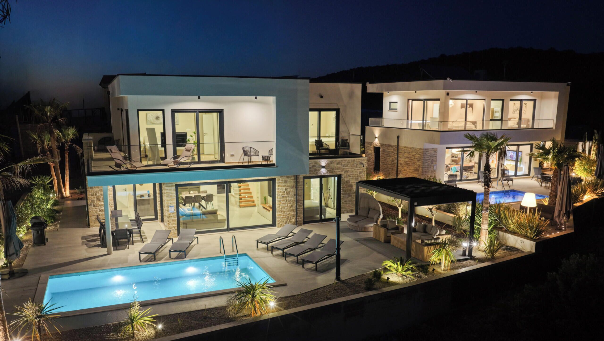 A modern two-story house with a swimming pool, outdoor seating, and a covered patio area.