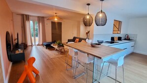 Una cocina moderna con una isla de madera, taburetes blancos tipo barra e iluminación colgante.