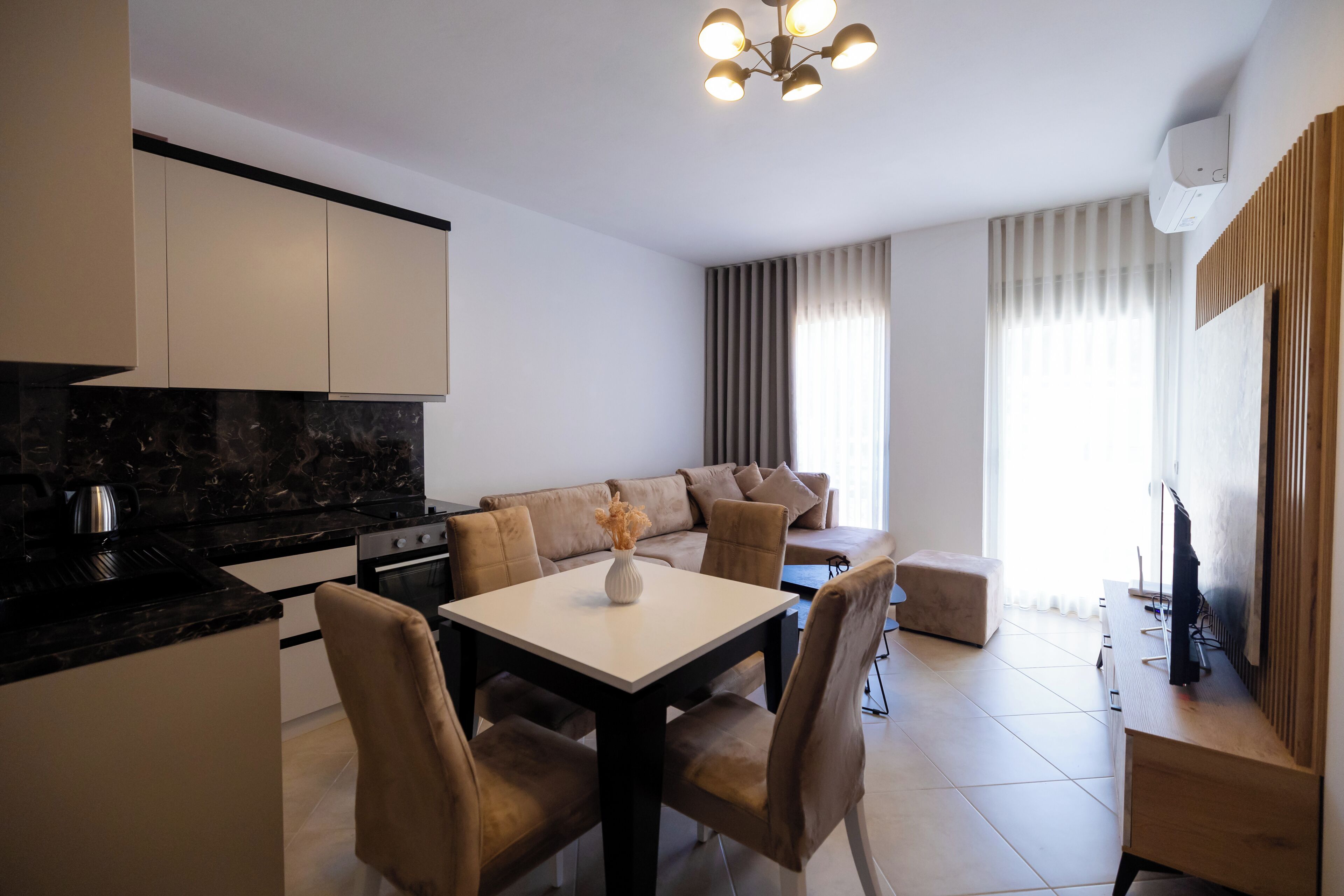 A modern kitchen with a dining area, a sofa, and a TV.