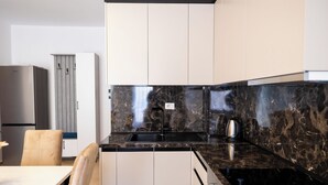 Una cocina moderna con encimera de mármol negro, pileta de acero inoxidable y una tetera.