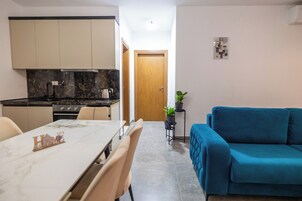 Egy kompakt, multifunkcionális lakótér, amelyben konyha, étkező és egy kanapé is található.