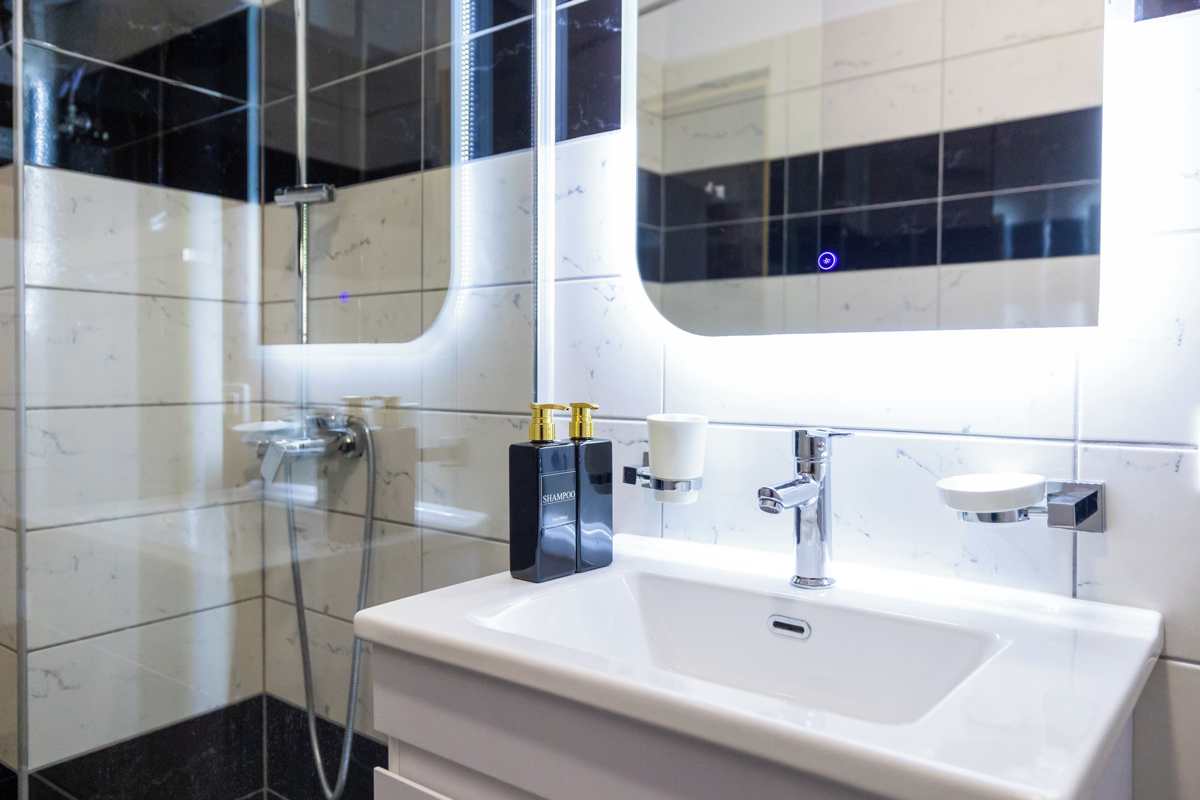 Une salle de bain moderne avec un lavabo blanc, des robinetteries chromées et une cabine de douche en verre.