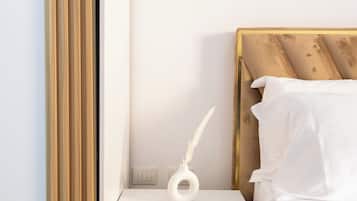 Une chambre à coucher avec une tête de lit en bois, du linge de lit blanc, une table de chevet avec un vase blanc et un tiroir.