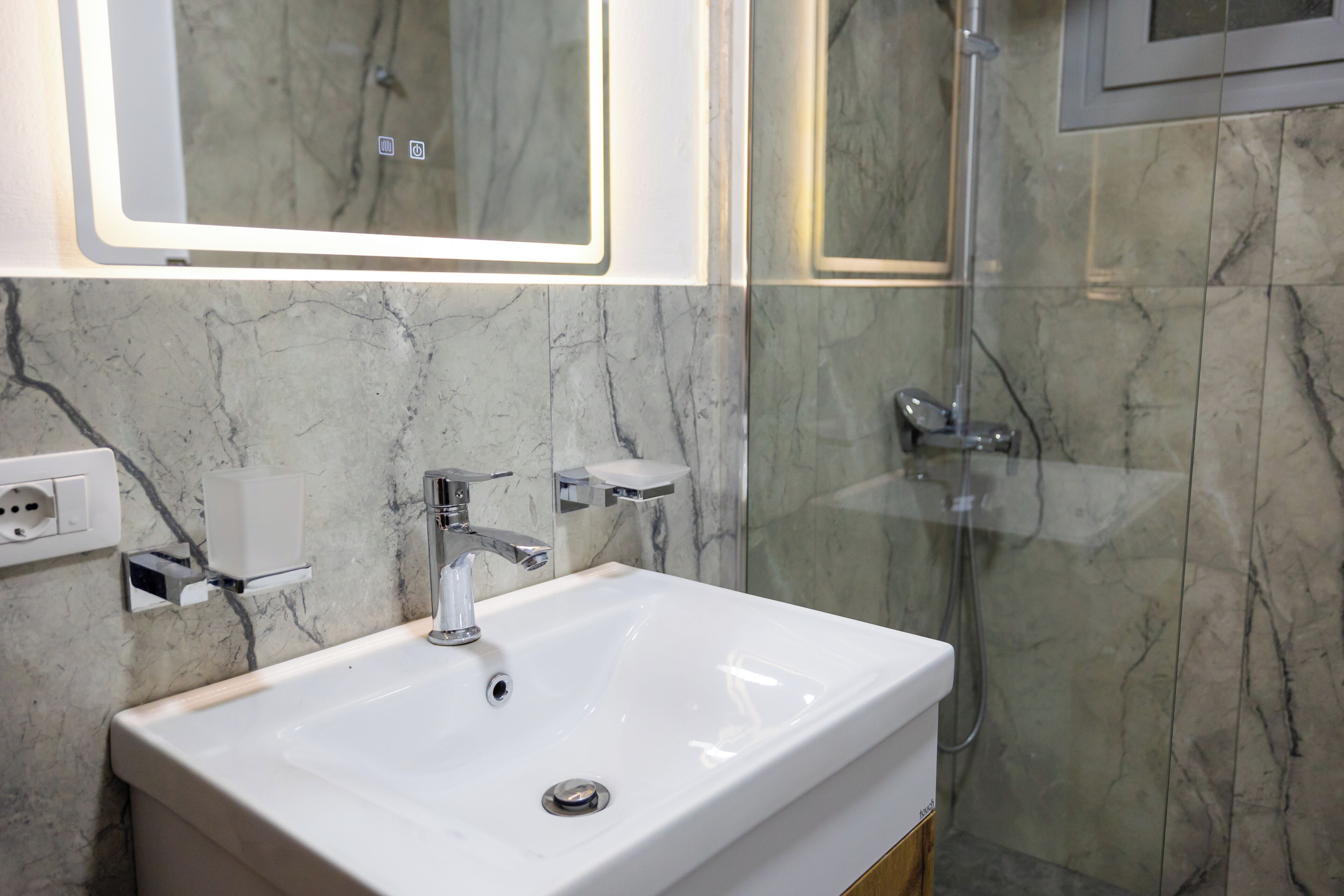 A bathroom with a white sink, a mirror, and a shower.