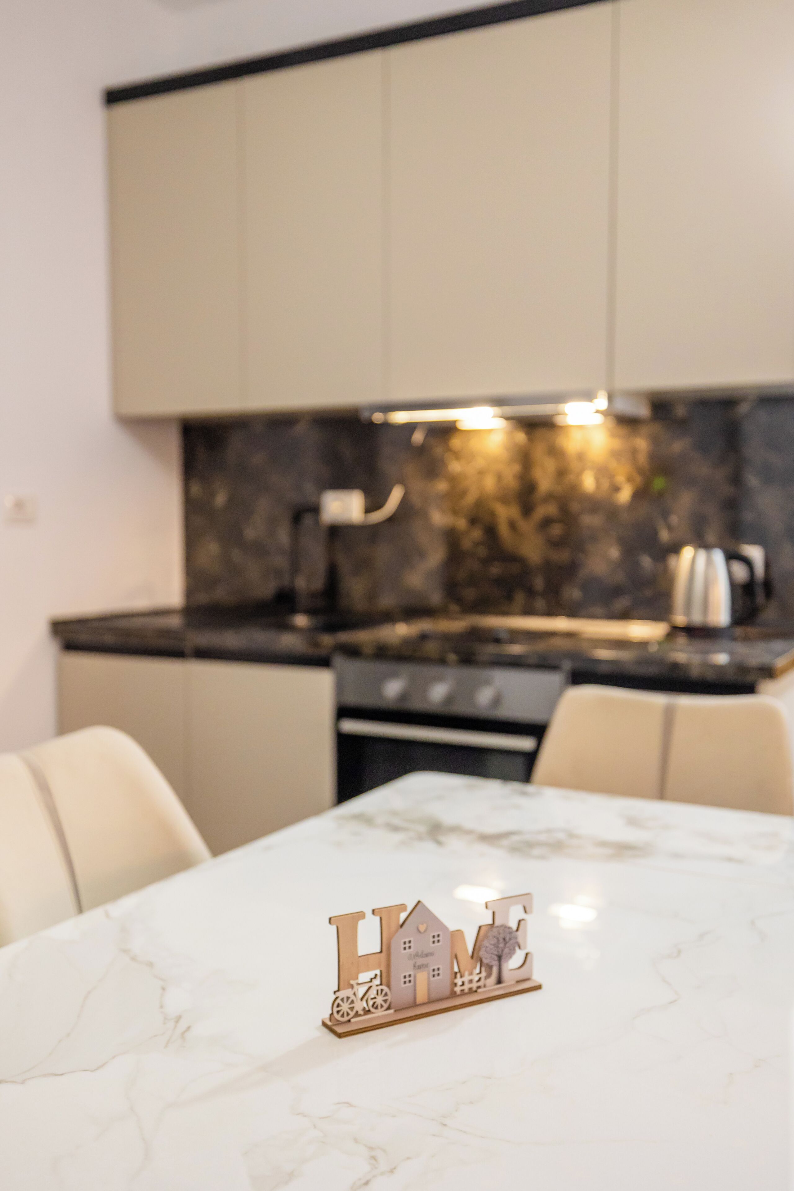 A modern kitchen with marble countertops, a built-in oven, and a dining area with a marble table.