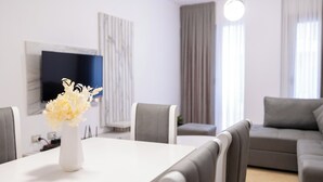 Una sala de estar moderna con una mesa de comedor, un sofá y un televisor montado en la pared.