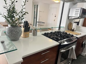 Une cuisine moderne équipée d’une cuisinière à gaz, d’un four et d’un îlot central avec un plan de travail en verre.