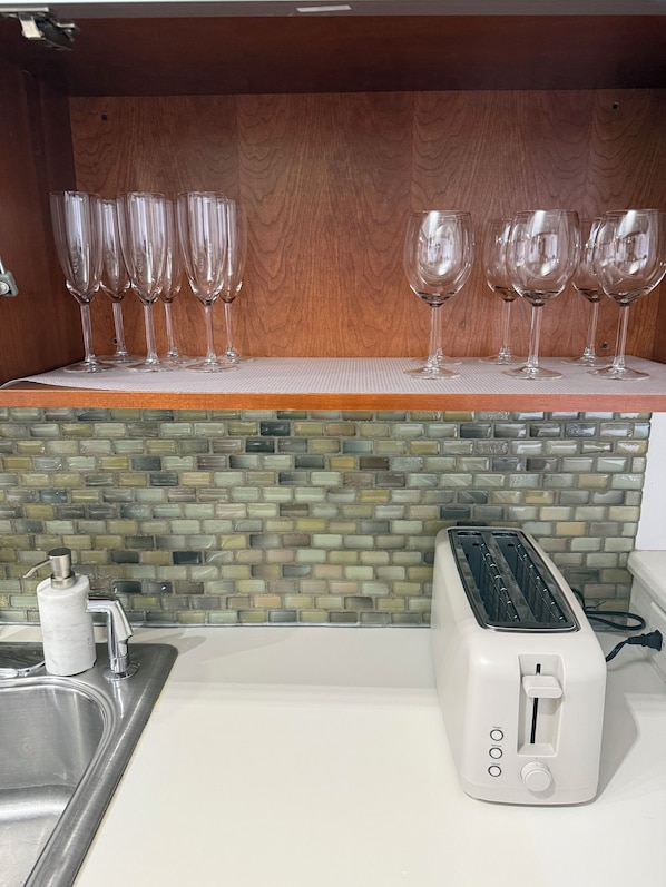 Eine Küche mit Holzausziehtisch, Fliesenrückwand, Spüle aus Edelstahl und einem weißen Toaster.
