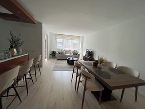 En moderne stue med spiseområde, sofa, fjernsyn og en plante.
