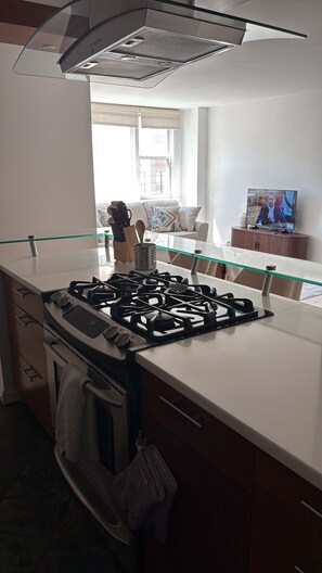 A modern kitchen with a gas stove, oven, and a glass-top dining table.
