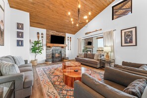 A living room with a fireplace, sofas, a coffee table, and a TV. - Lake View~Hot Tub, Arcade, Pool, 1mi to SilverDC (Branson)