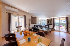 Een moderne woonkamer met een eethoek, een bank en een glazen deur naar een terras.