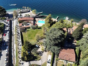 An aerial view of a coastal area with a swimming pool, a dock, and a road with parked cars. - Dada in Varenna - Relaxing Lake House (Perledo)