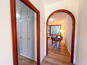 A hallway with a wooden door frame, a dining area with a table and chairs, and a window with a view of trees. - Dada in Varenna - Relaxing Lake House (Perledo)