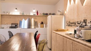 A modern kitchen with wooden cabinetry, a stainless steel range hood, and a white refrigerator. - Design Mountain Home in Center of Bormio (Bormio)