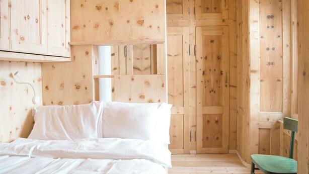 A wooden room with a bed, a chair, and wooden walls. - Design Mountain Home in Center of Bormio (Bormio)