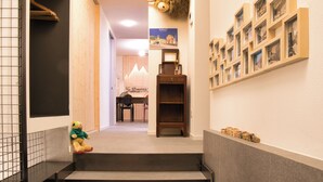 A hotel corridor with a staircase, a mounted animal head, a desk with a chair, and a wall with framed pictures. - Design Mountain Home in Center of Bormio (Bormio)
