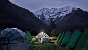 A series of dome-shaped tents in a mountainous area with snow-capped peaks in the background.
