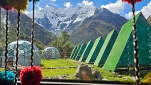 A view of a mountainous landscape with green tents and a greenhouse.