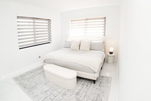 A bedroom with a bed, a bench, a nightstand, and a window with blinds. - Luxury 1 King BR Retreat near Calle Ocho (Miami)