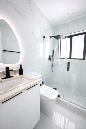 A modern bathroom with a glass shower enclosure, a white marble countertop, and a large mirror. - Luxury 1 King BR Retreat near Calle Ocho (Miami)