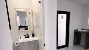 Une salle de bain moderne avec un lavabo blanc, un miroir et des armoires.
