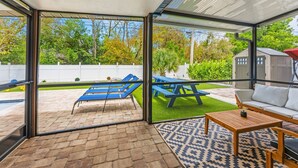 Una veranda coperta con piscina, poltrona a sdraio, tavolo e divano.